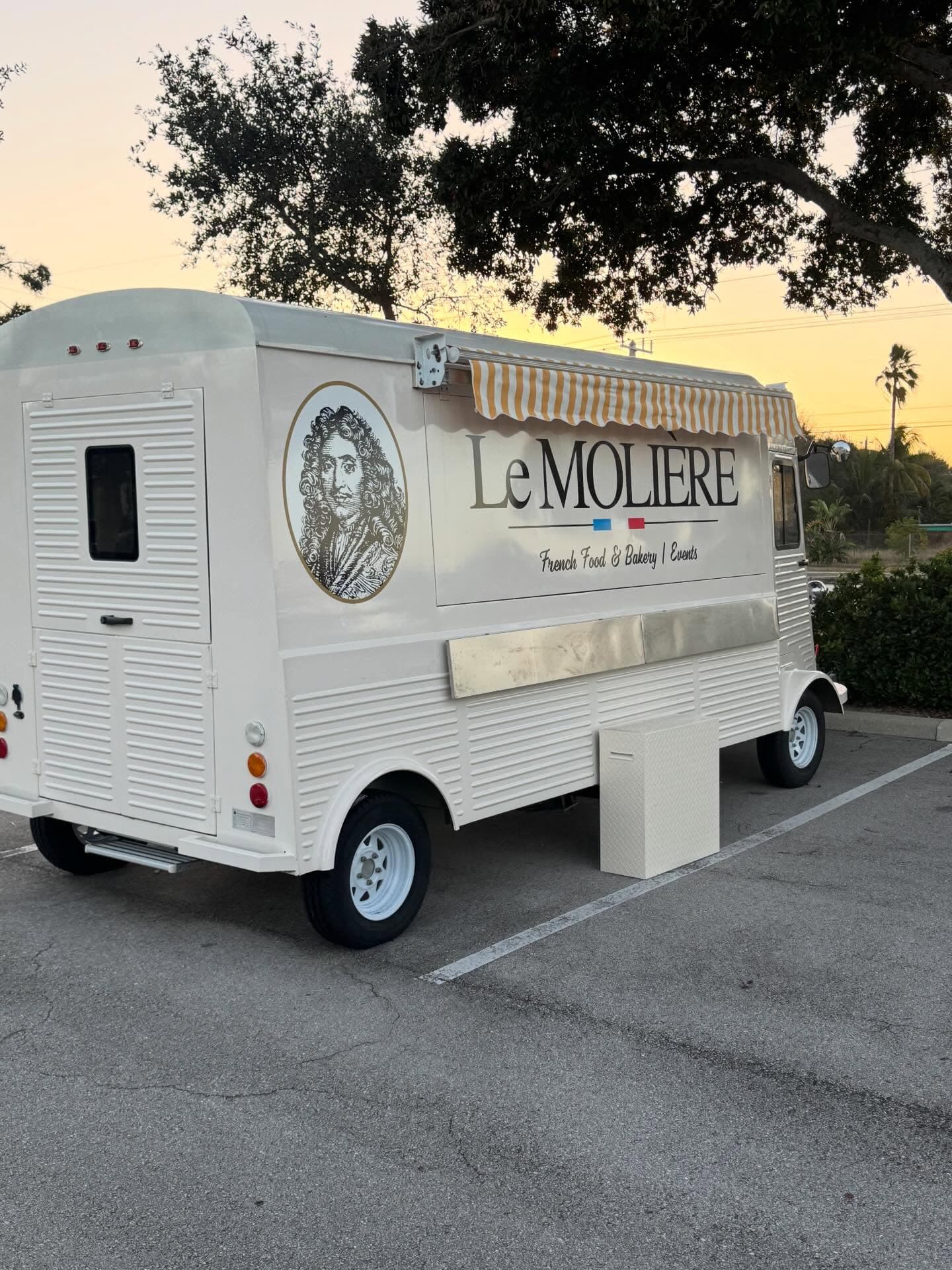 The Le Molière vintage French food truck at sunset under oak trees