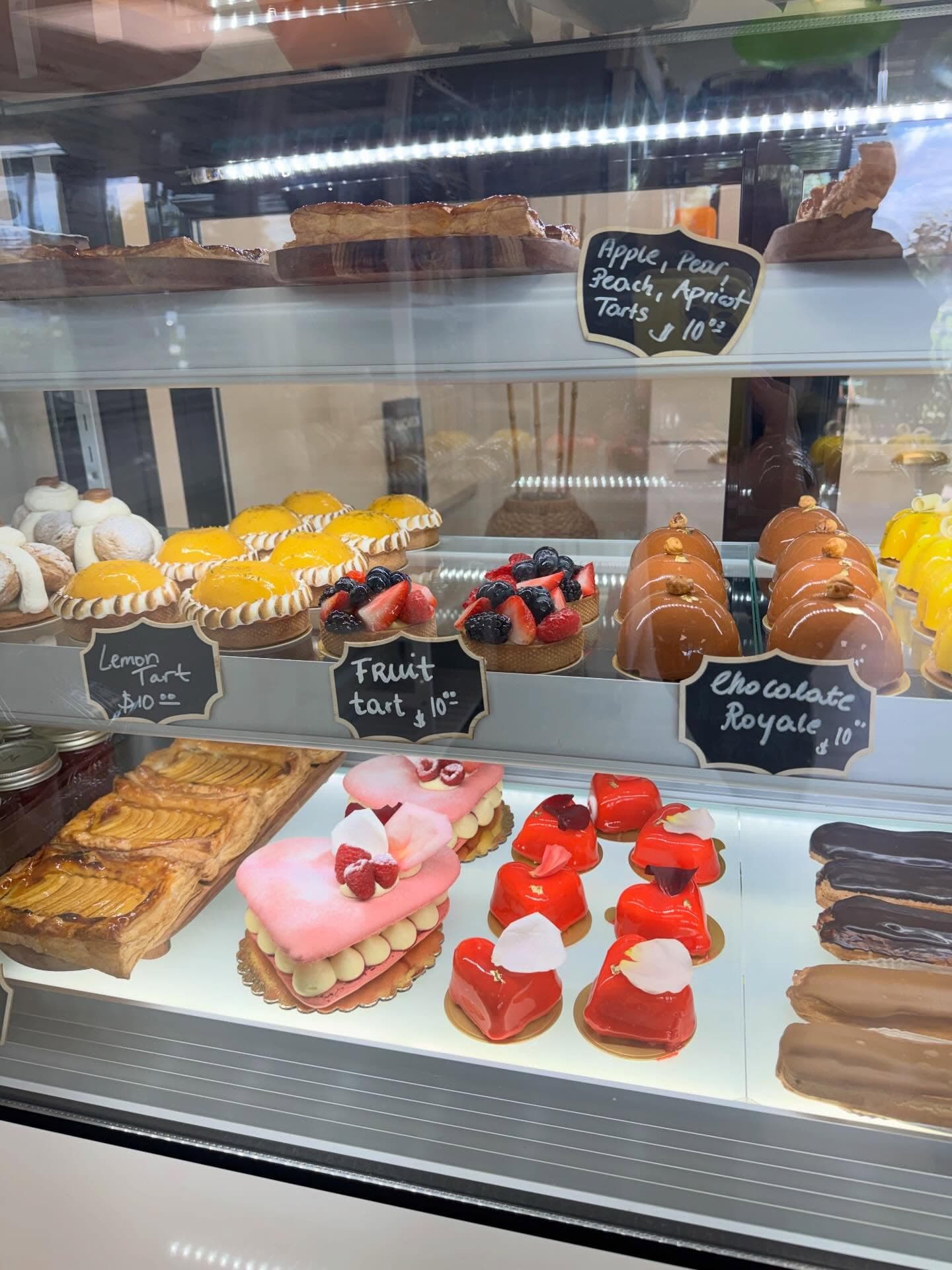 Pastry display case with hand-written chalk signs for lemon tart, fruit tart and chocolate royale