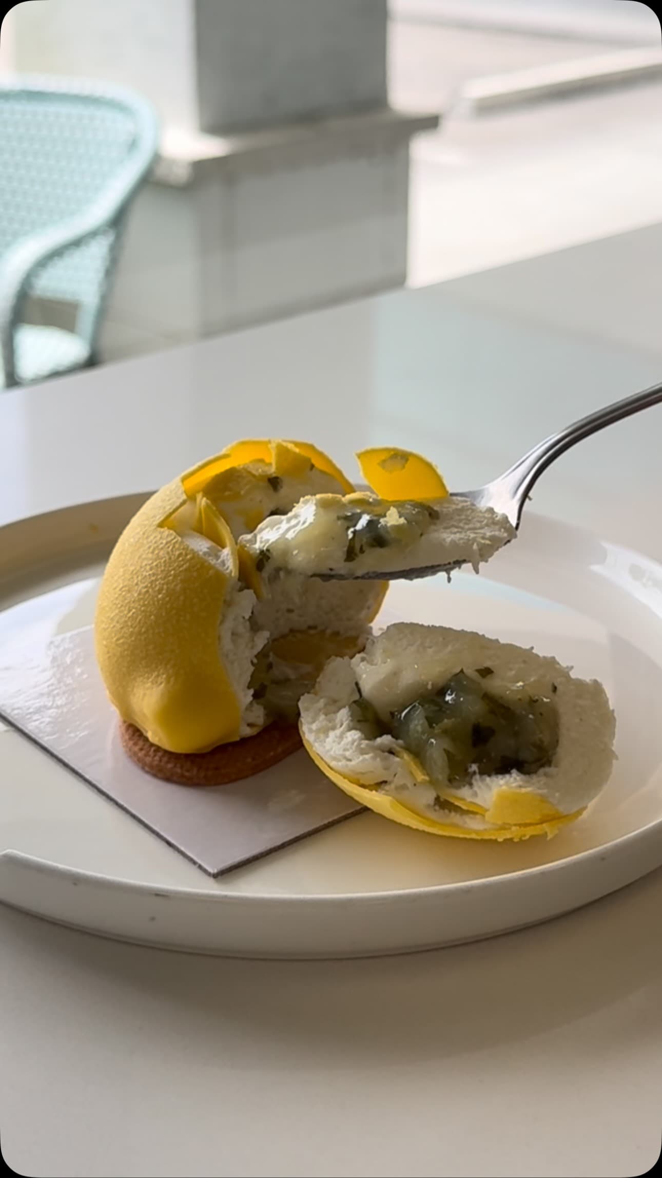 A bite of a lemon and herb dessert, showing the mousse and compote inside