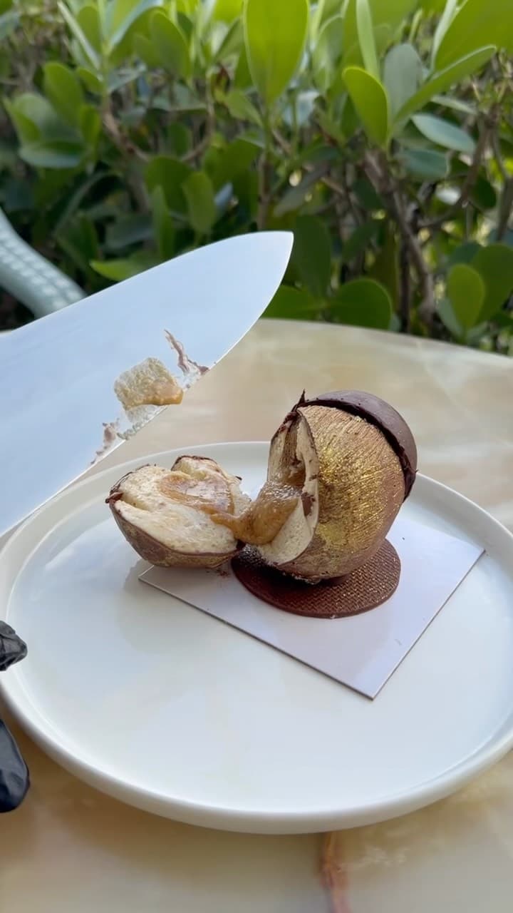 A coconut-shaped trompe-l'œil pastry sliced open to reveal the filling
